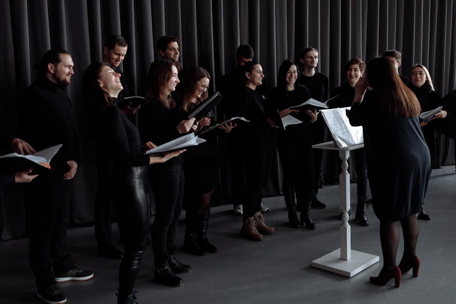 A group of men and women singing with a conductor during choir practice.