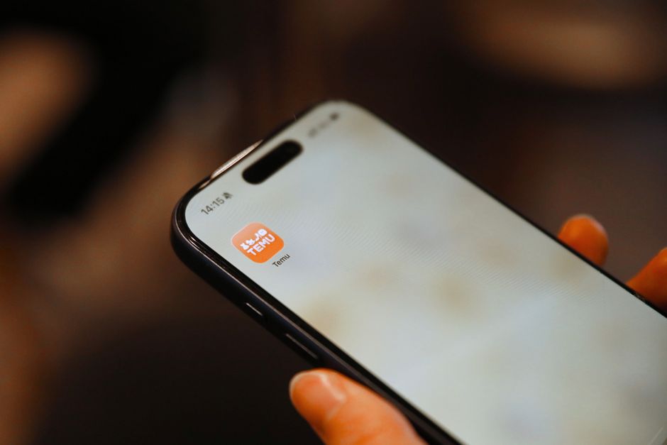 Hand holding smartphone with a shopping app icon visible, focusing on digital convenience.