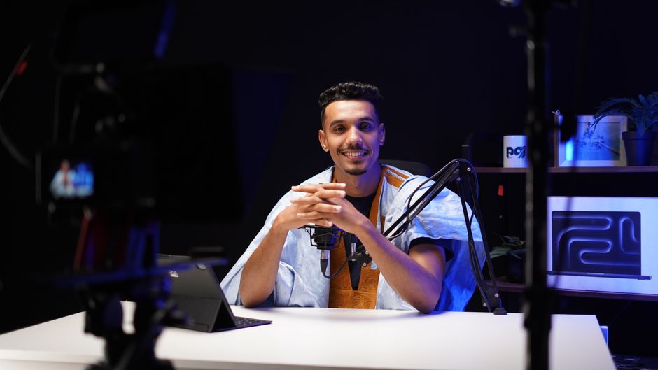 A confident podcaster speaking into a microphone in a modern studio setting.