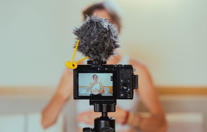 Elderly woman engages in vlogging using camera and microphone, embracing modern technology.