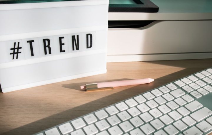 Contemporary workspace featuring a light box showing '#trend,' a pink pen, and a keyboard.