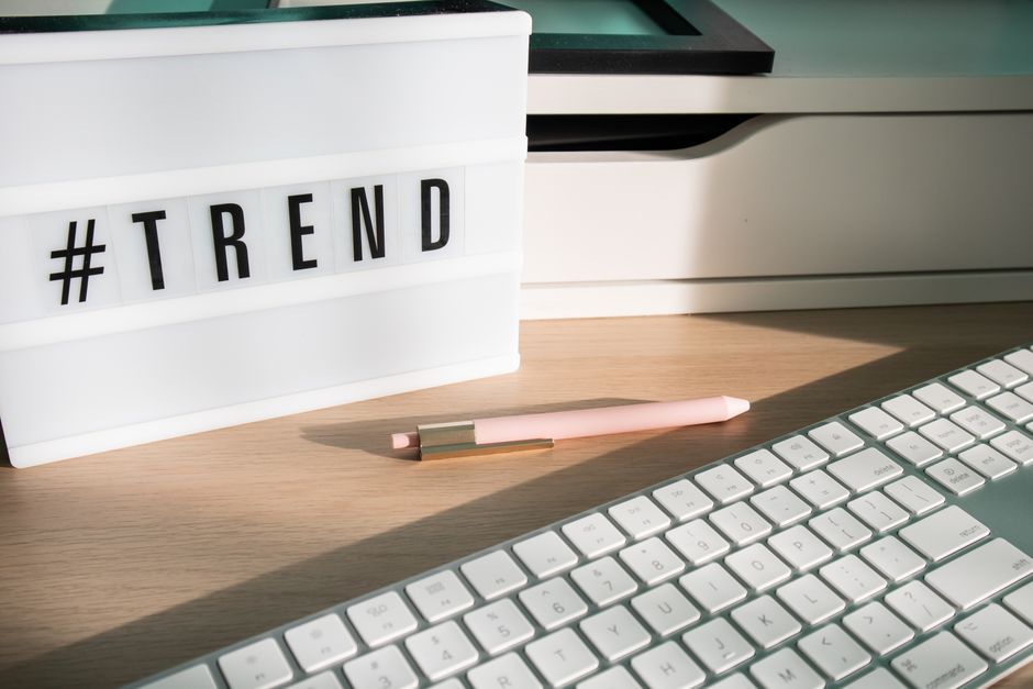 Contemporary workspace featuring a light box showing '#trend,' a pink pen, and a keyboard.