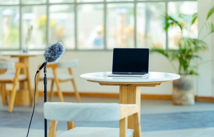 A modern workspace featuring a laptop and microphone setup in a bright, airy room.