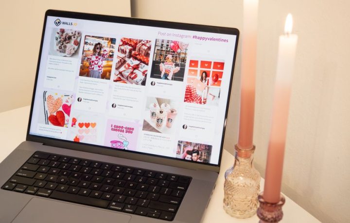 A romantic setup featuring a laptop with Valentine's posts and pink candles, perfect for a cozy atmosphere.