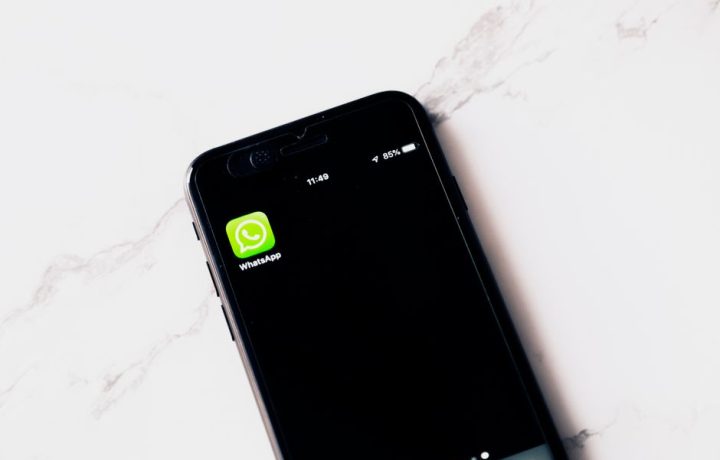 Close-up image of a smartphone displaying WhatsApp on a white table.