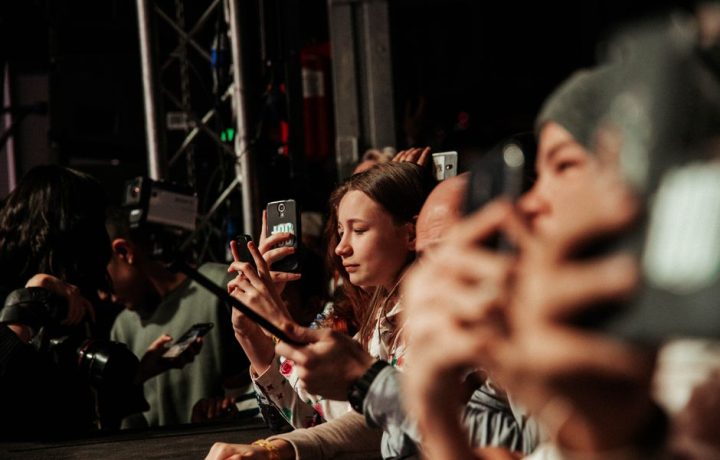 People eagerly capturing a live event on their smartphones, showcasing audience engagement.