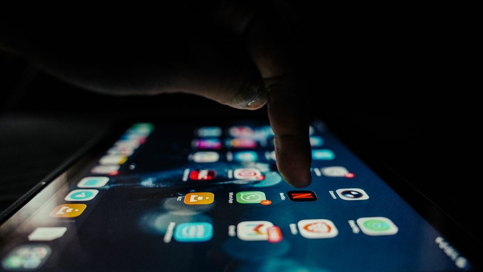 Person interacting with smartphone apps in dim light, highlighting digital interaction.