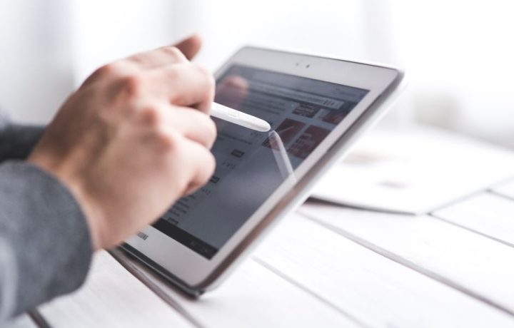 Close-up of a hand using a stylus on a tablet, showcasing digital technology interaction.