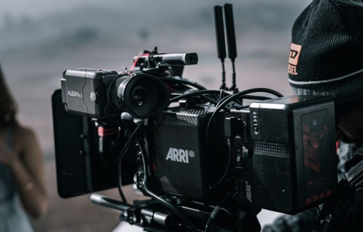 Close-up of a professional filmmaking camera setup on an outdoor set with blurred background.