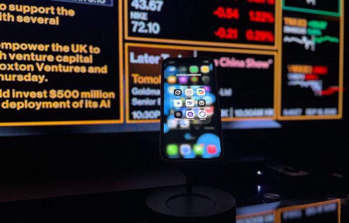 Smartphone displaying AI apps in front of a financial data screen in London.