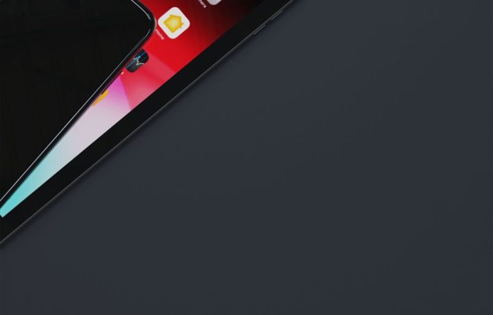 Top view of smartphone and tablet on dark gray surface with ample copyspace.