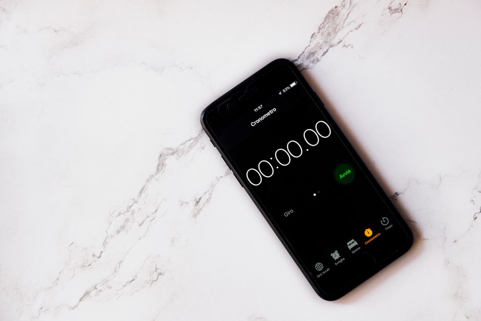 Close-up of a smartphone displaying a stopwatch on a marble surface.
