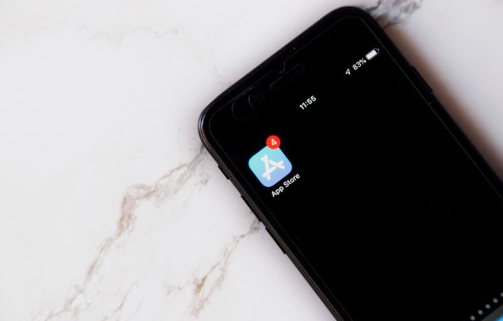 Close-up of an iPhone showing a notification on the App Store icon against a marble background.