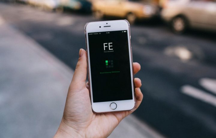 Close-up of a smartphone with an app on screen held by a person in an urban setting.