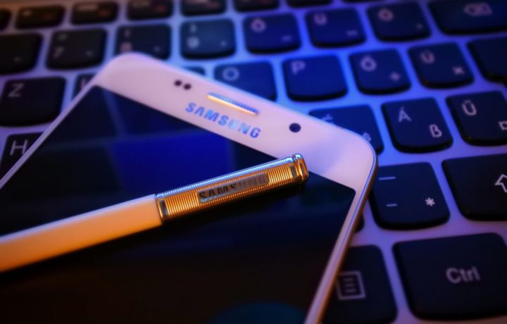 Close-up of a smartphone with a stylus on a keyboard, highlighting modern mobile technology.