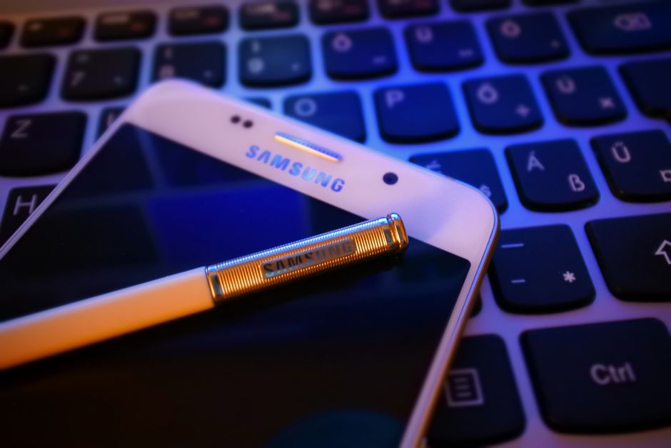 Close-up of a smartphone with a stylus on a keyboard, highlighting modern mobile technology.