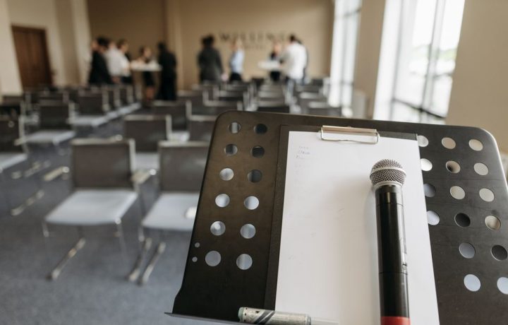 Close-up of a microphone on a stand in a conference room setting.