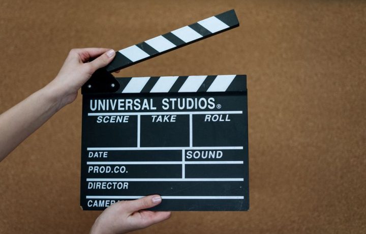 Close-up of Universal Studios clapboard on a cork background held by hands.