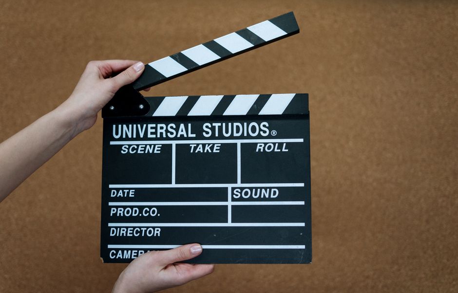 Close-up of Universal Studios clapboard on a cork background held by hands.