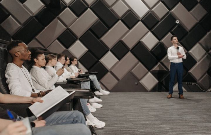 Diverse group of professionals attending a seminar indoors, listening intently to a presenter.
