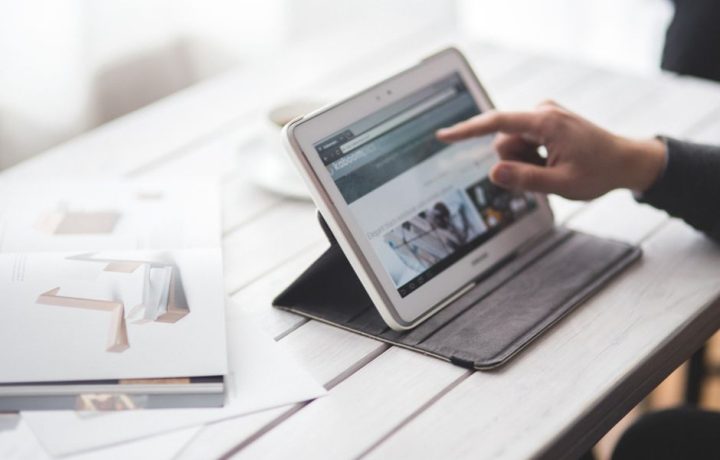 A person using a tablet on a sleek desktop, showcasing a contemporary workspace setting.