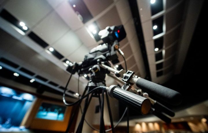 From below of modern professional video camera with wires placed on tripod in studio on blurred background