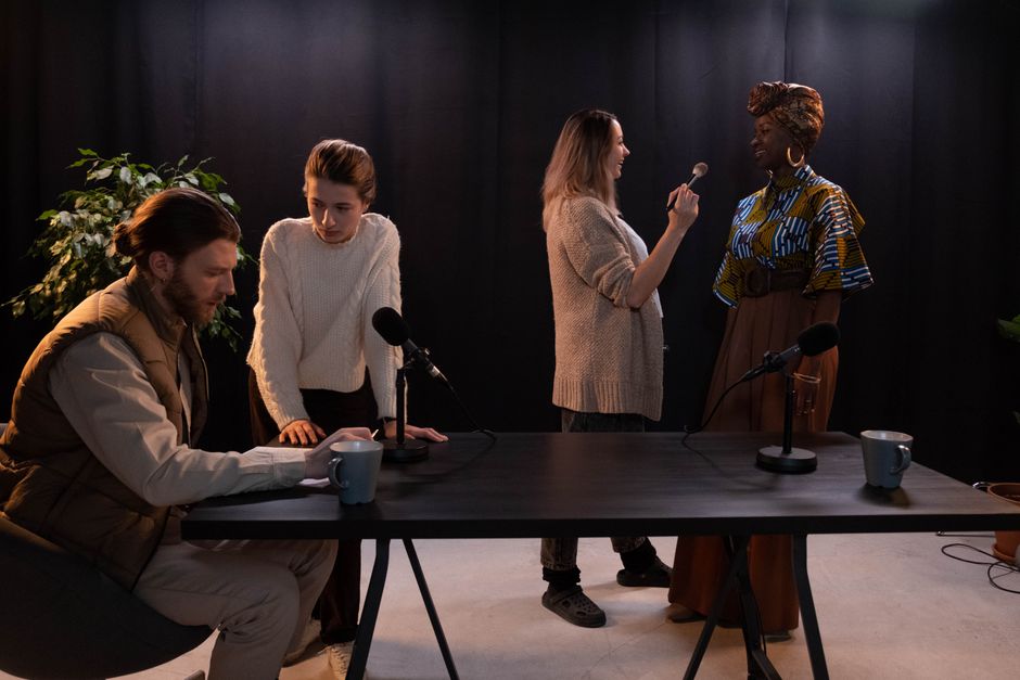 Four people in a studio setting with microphones, engaged in conversation.