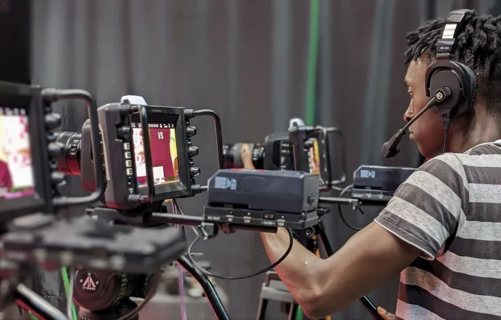 A videographer fine-tunes camera gear while preparing for a live streaming session in a professional studio