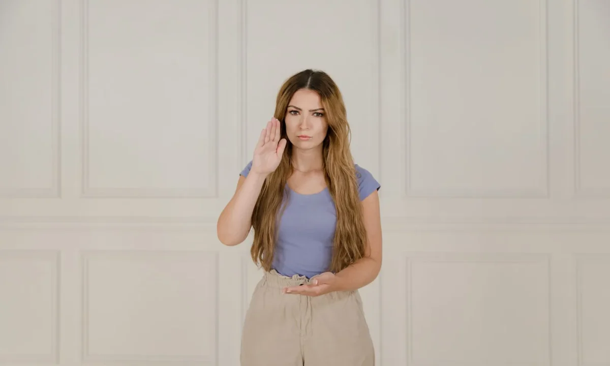 A woman in a blue t-shirt demonstrates sign language, emphasizing effective communication with teleprompters