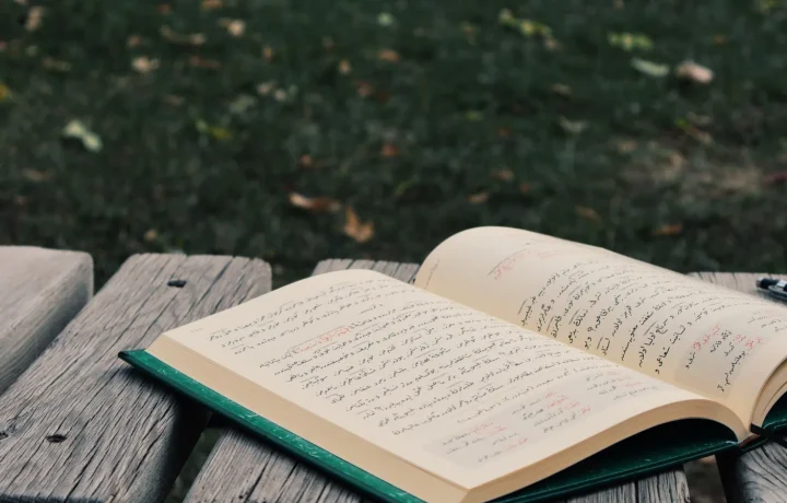 An open book with Arabic script on a wooden bench, symbolizing the art of crafting teleprompter script tips