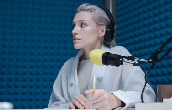 Confident woman hosting a podcast in a soundproof studio, highlighting trends in teleprompter technology