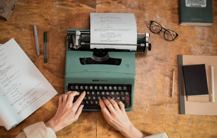 Hands typing on a classic typewriter surrounded by documents, illustrating the art of writing for video