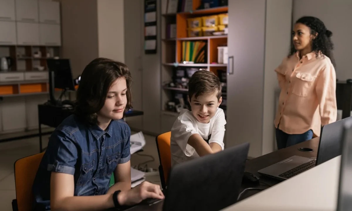 Students in a classroom using laptops while a teacher oversees, highlighting the role of teleprompters in education