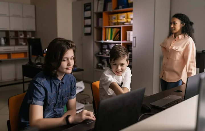 Students in a classroom using laptops while a teacher oversees, highlighting the role of teleprompters in education