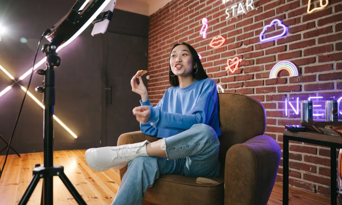 Young Asian woman streaming live with neon lights, actively engaging viewers through technology and creative content