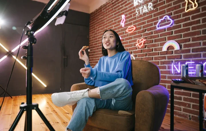 Young Asian woman streaming live with neon lights, actively engaging viewers through technology and creative content
