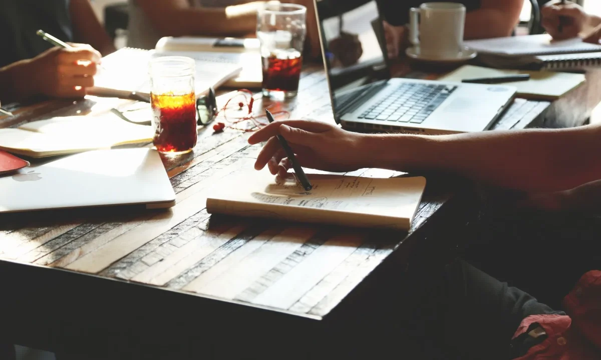A group of adults collaborating in an office meeting, sharing essential tips with notes and laptops