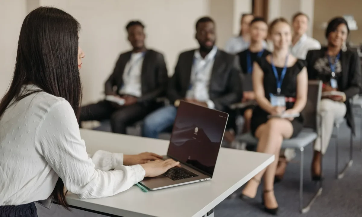 A professional woman confidently presenting to a diverse group of colleagues in a modern office setting