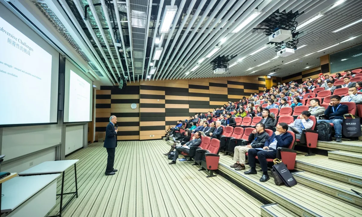 A speaker presents confidently to an engaged audience in a sleek auditorium, highlighting teleprompters in corporate training