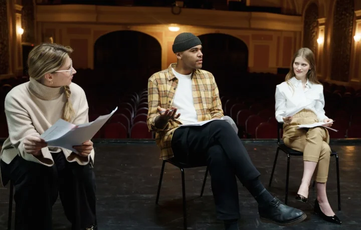 Actors rehearsing on stage with scripts, illustrating script writing for teleprompters and delivery practice