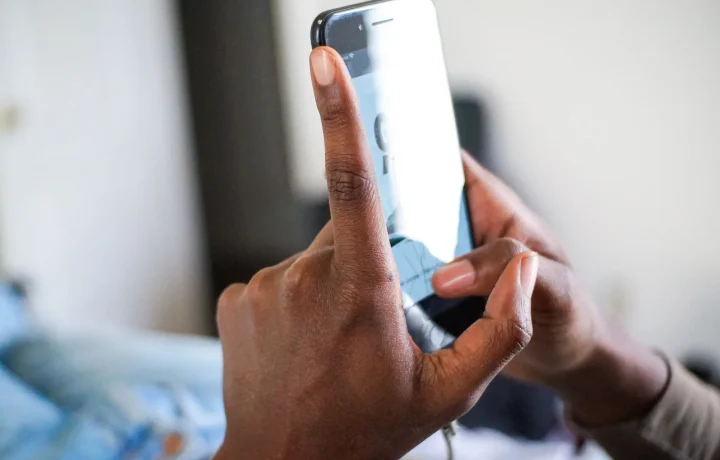 African American hand demonstrating a texting gesture on a smartphone, highlighting teleprompter app comparisons in use