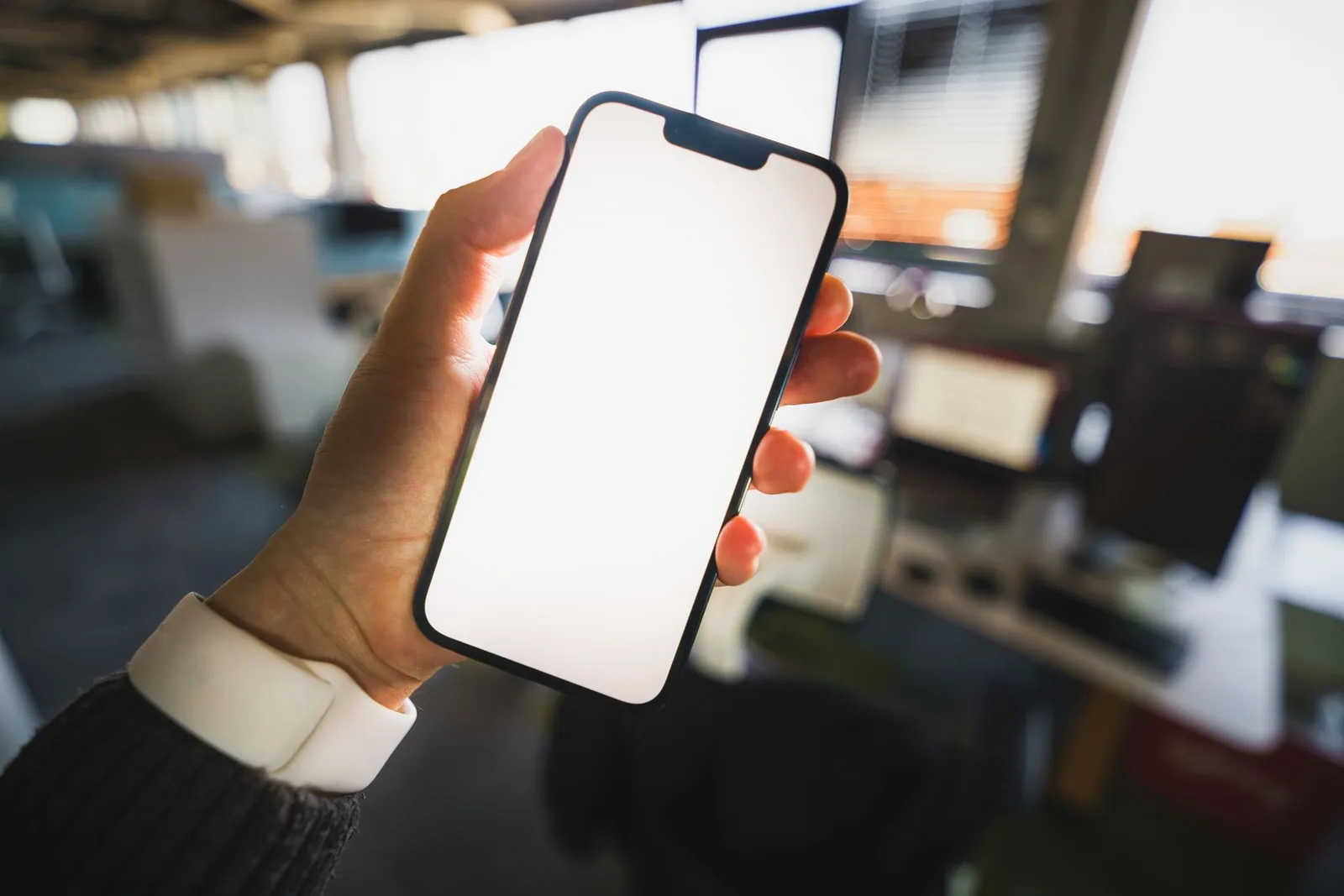 Blank phone screen held up in an office, ideal for noting your use case and requirements