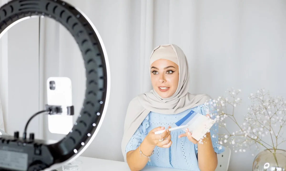 Building on-camera confidence with a ring light while a young Muslim woman records a video on her phone