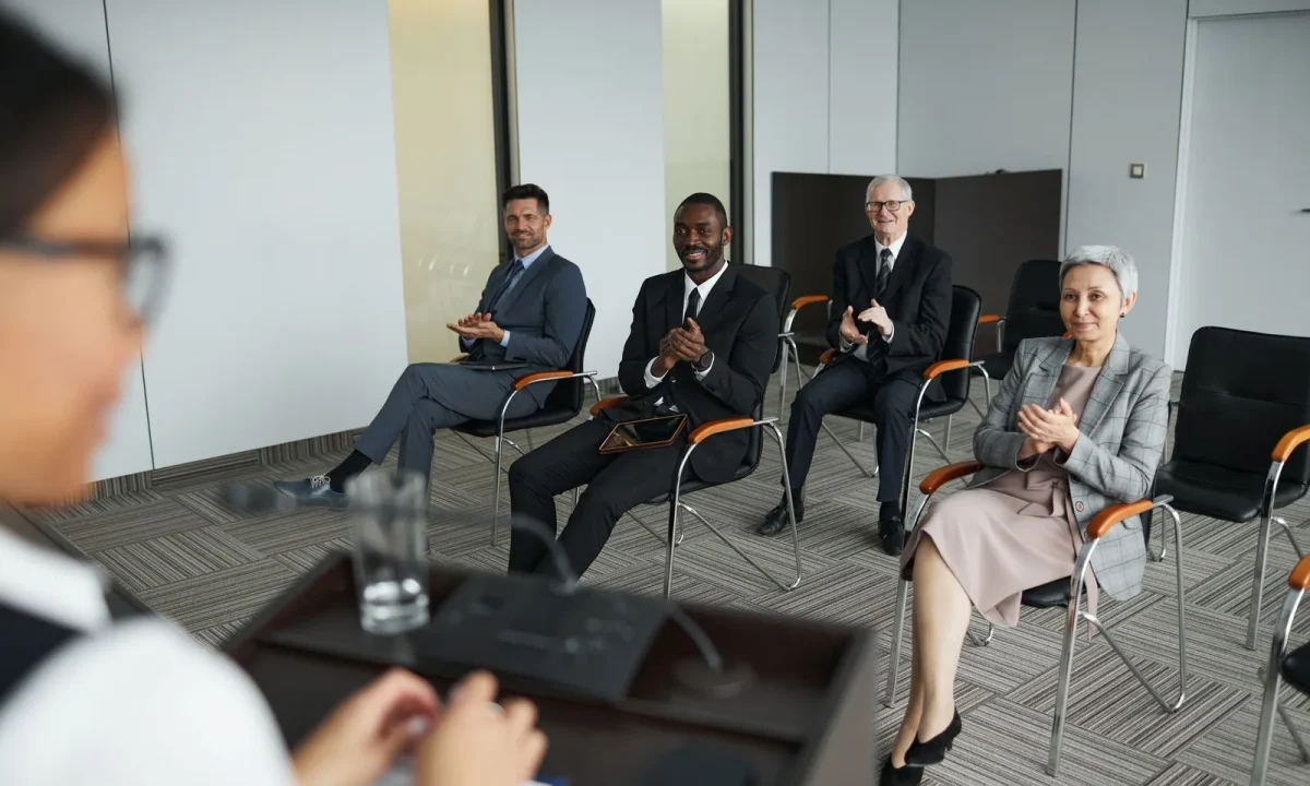 Business audience clapping in a conference room, showing audience engagement teleprompters in action