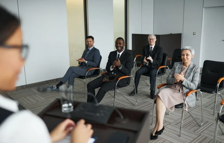 Business audience clapping in a conference room, showing audience engagement teleprompters in action