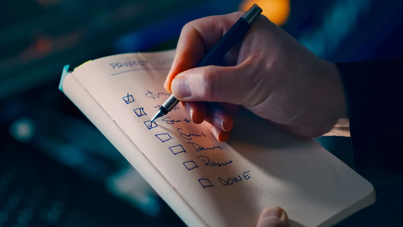 Close-up of a hand writing a checklist while preparing a teleprompter script for smooth recording