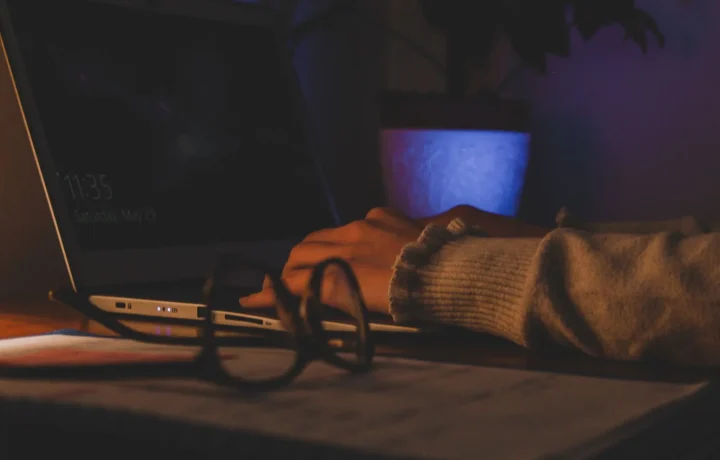 Cozy workspace with hands typing on a laptop, emphasizing the importance of effective script formats in writing