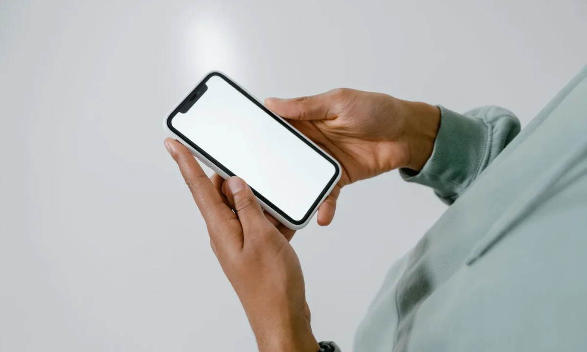 Hands holding a smartphone with a blank screen, ideal for showcasing teleprompter app comparisons
