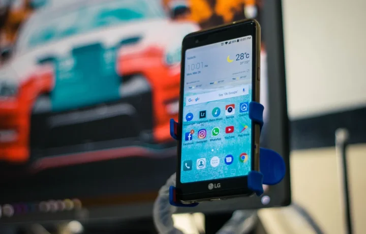 LG smartphone in a car holder displaying various teleprompter app features on the screen