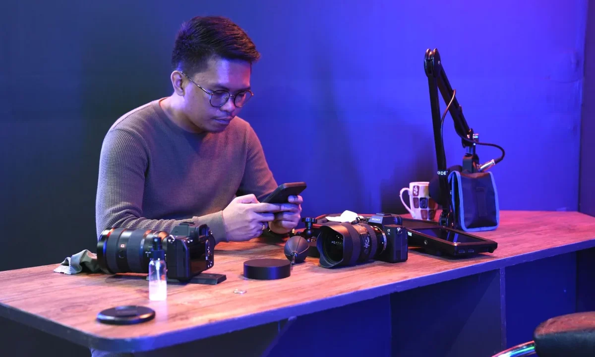Man at a desk speaking to cameras while reading a script on a smartphone, showing the future of teleprompters in action